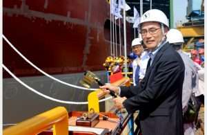 Takaaki Anraku, President, Kokusai Cable Ship Company, cutting the rope to break the milk pot against the vessel’s hull
