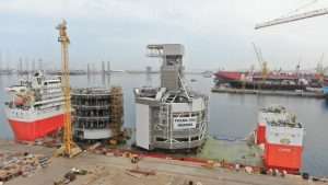 The TMS components being loaded onto a heavy lift vessel prior to departing Drydock World